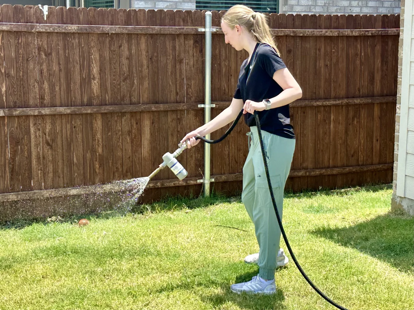 Rhino Scoop pump-up sprayer applying deodorizer and sanitizer treatment in a North Texas yard